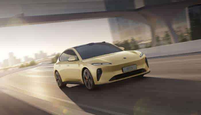 Best chinese electric cars in europe 2026 | tycoonstory media Yellow sporty electric car driving at speed on a curved elevated highway with an urban skyline in the distance (sunset light).