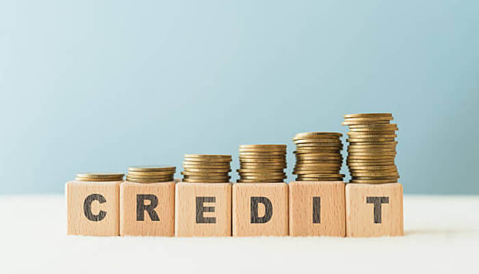 Building credit through responsible borrowing habits | tycoonstory media Stacks of coins rising above wooden credit blocks, illustrating money management and responsible borrowing habits.
