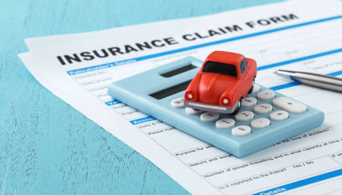 Why are auto insurance claims sometimes challenging? | tycoonstory media Toy car placed on calculator over insurance claim form representing financial calculations and disputes in insurance processes, including scenarios linked to workplace injury compensation and claims challenges.