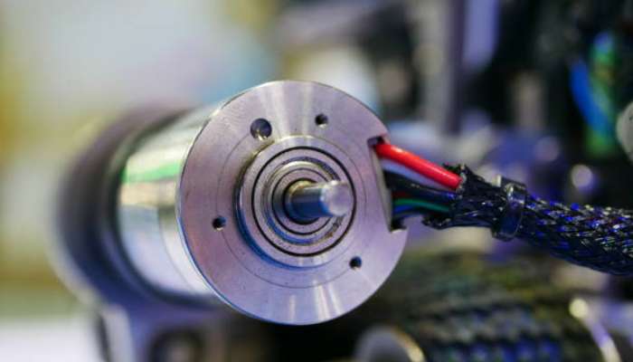 High-torque 24v bldc motor 1 | tycoonstory media Close-up of a metal motor shaft with red and blue wires and braided cable sleeve in the background.