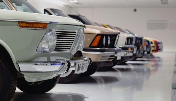 How to sell your car in brisbane quickly and without hassle 1 | tycoonstory media Row of vintage cars in a bright showroom, closest green car with chrome bumper and visible license plate, followed by beige and other colored classics.