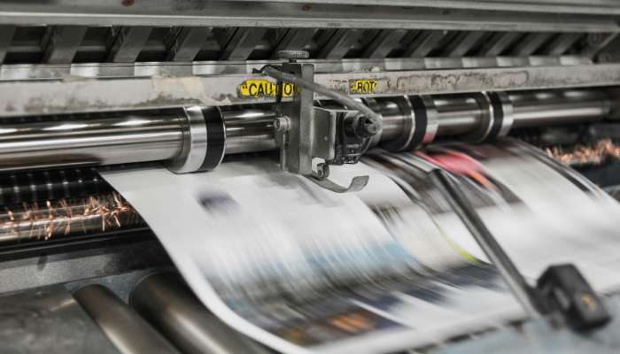 Laminating adhesives 1 | tycoonstory media Industrial printing press in motion with sheets feeding through rollers
