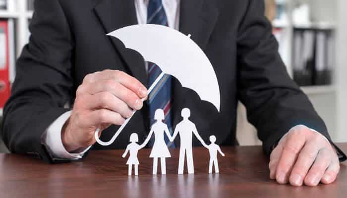 Life insurance - tycoonstory | tycoonstory media Business professional holding an umbrella symbol over a family cutout figure representing employee protection and insurance benefits, illustrating “which of the following is considered part of your workplace benefits? ” through visual metaphor of financial and family security.
