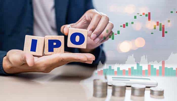 Monitoring upcoming ipo opportunities through market timing and listing activity 1 | tycoonstory media Hands hold wooden blocks spelling ipo, with stock charts and coins in the background indicating an initial public offering.