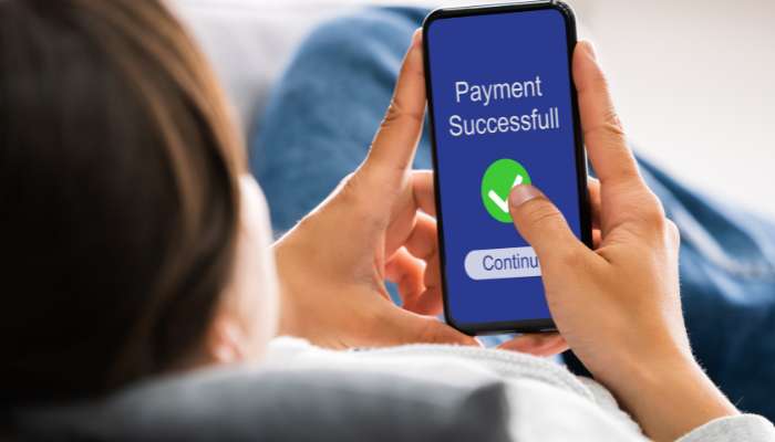 People trust online payments more than before | tycoonstory media Phone screen shows a payment success message with a green checkmark and a continue button as a person taps it.
