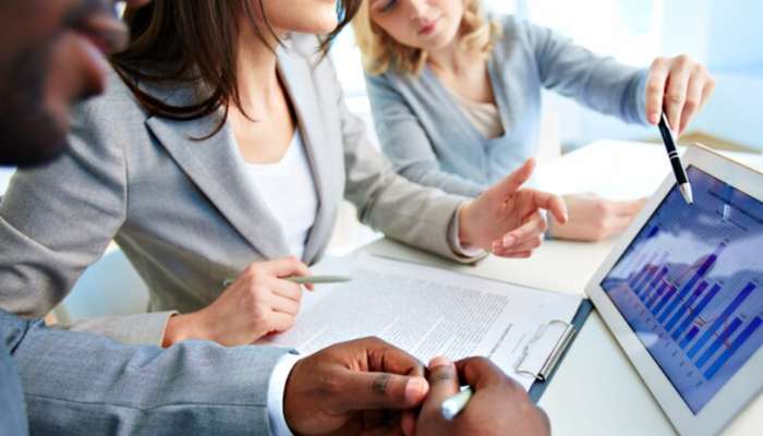 The growth finance playbook how ambitious entrepreneurs navigate capital without losing control 1 | tycoonstory media Three business professionals review charts on a tablet during a meeting, with pens and documents on the table in a bright office.