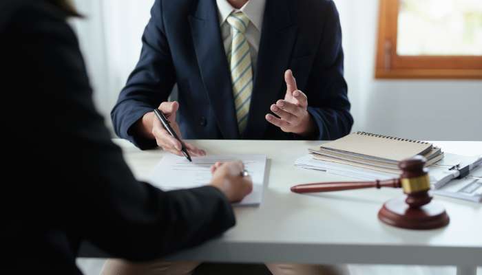 Tips for choosing a personal injury lawyer 2 | tycoonstory media Lawyer in a navy suit signs papers at a desk, with a gavel and files nearby.