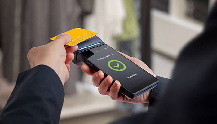 Untitled-1 | tycoonstory media Person using a handheld card reader to tap a credit card for payment.