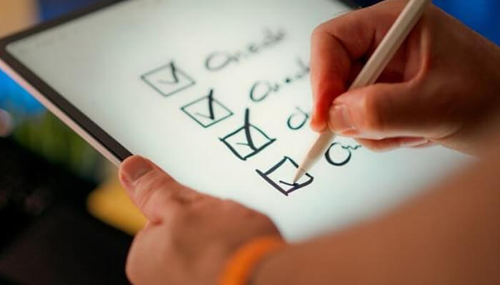 What quality means in australian residential aged care | tycoonstory media Person uses a stylus to check off items on a tablet-based checklist with visible checkmarks on the screen.