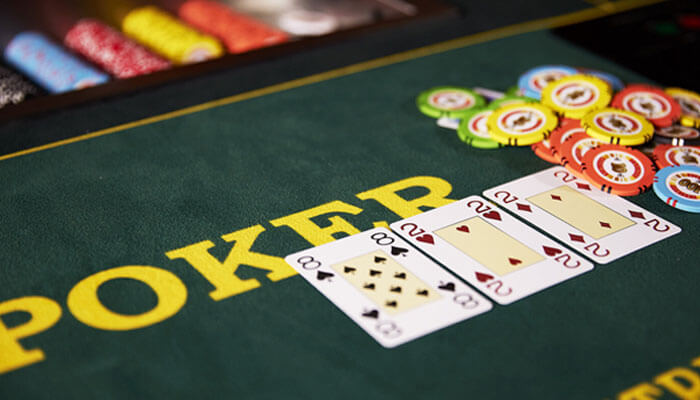 Video poker: control and familiarity - tycoonstory | tycoonstory media Close-up of a poker table with four face-up cards in a row and colorful poker chips nearby on green felt with 'poker' text visible in the background.