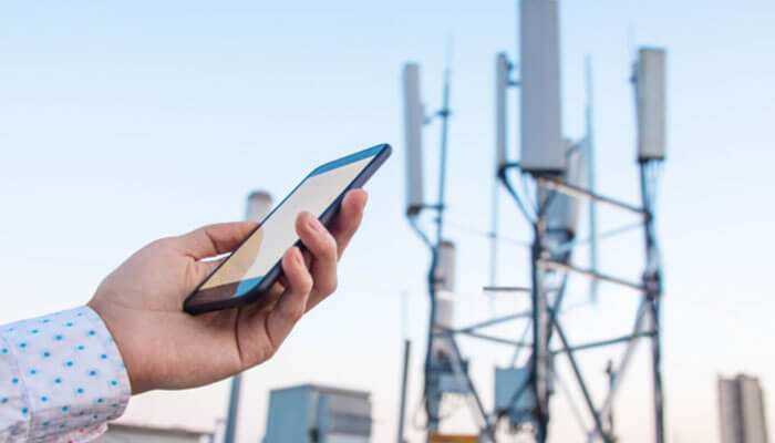 Behavioral signals beyond the ip address - tycoonstory | tycoonstory media Person holding a smartphone near cellular antennas on a rooftop, suggesting mobile network activity