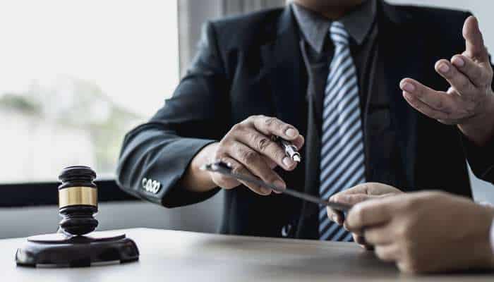 Why specialized legal defense matters in complex fraud cases 1 | tycoonstory media Judge in a suit with a gavel on the desk as another person hands him a small object, suggesting a legal proceeding.