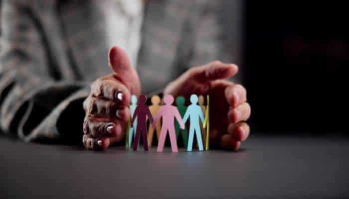 5 employment law mistakes new york startups make 1 | tycoonstory media Small colorful paper people held between two hands, symbolizing protection and care for a diverse community of individuals.