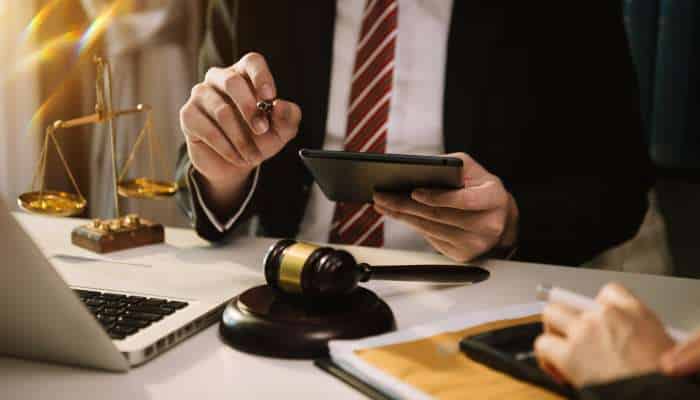 Accident claims 1 | tycoonstory media Lawyer using a tablet at a desk with scales of justice, a gavel, and documents nearby.