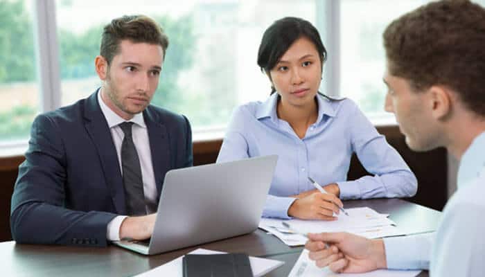 Your right to deal with insurers on fair terms - tycoonstory | tycoonstory media Three professionals in a meeting; a man in a suit uses a laptop while a woman takes notes and a colleague speaks.