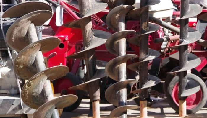 Augers deserve special attention | tycoonstory media A collection of heavy-duty augers and drilling tools used as excavator attachments for digging, foundation work, and earthmoving projects.