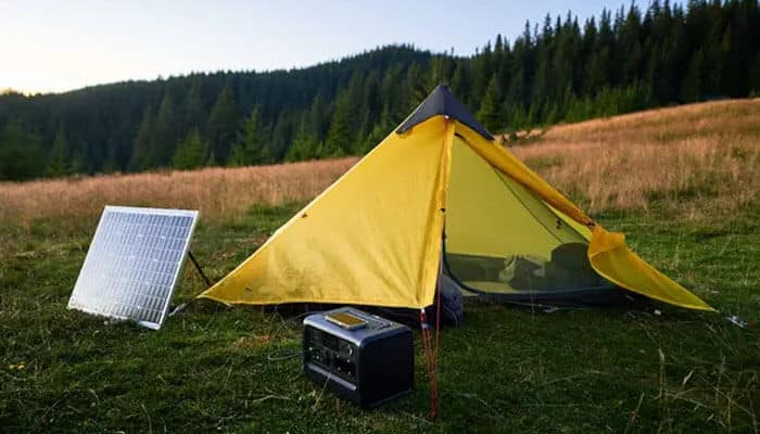 Match the battery to your setup - tycoonstory | tycoonstory media Lithium battery for camping connected with solar panel setup at a campsite, providing sustainable off-grid power for tents, caravans, and outdoor activities.