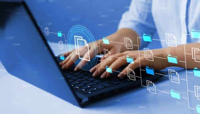 Digital rights management strategies that reduce content misuse 1 | tycoonstory media Person typing on a laptop with digital file icons and floating folders illustrating data transfer and cloud storage.