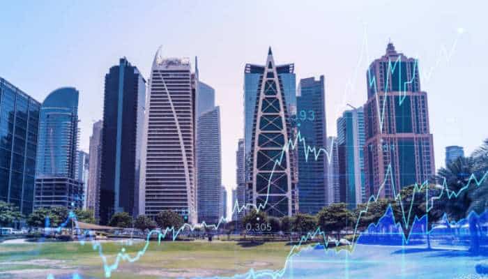 Emerging markets and the great rotation | tycoonstory media City skyline with glass skyscrapers and a blue stock market line graph overlaying the scene.