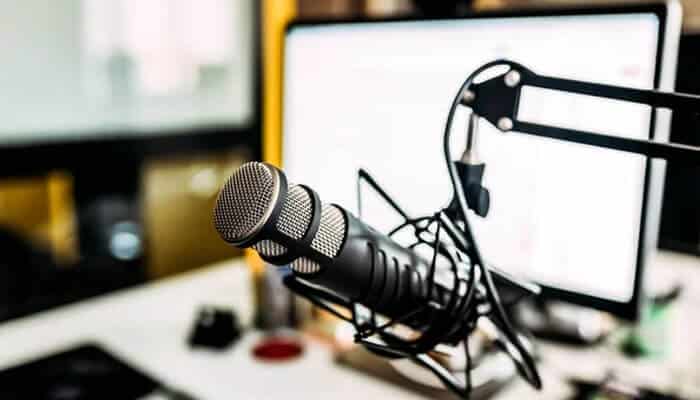 Add accessories only when needed - tycoonstory | tycoonstory media Podcast equipment basics workspace with a studio microphone, boom arm, and computer monitor showing a modern audio recording setup for podcasts and voice production.