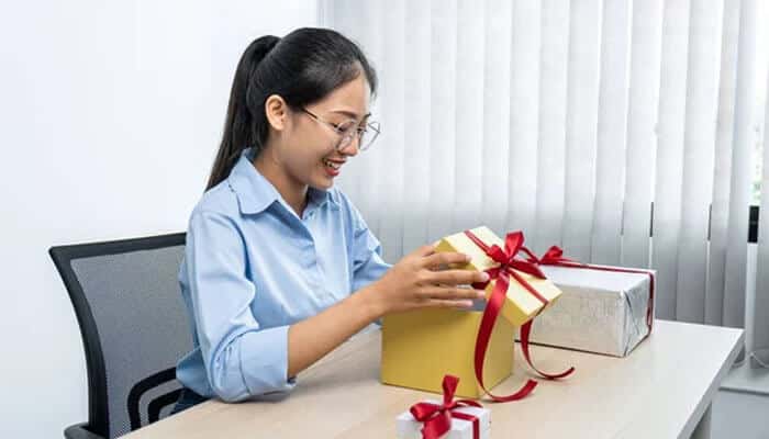 What are some key occasions for giving customised gifts to clients and employees? - tycoonstory | tycoonstory media Employee receiving corporate gifts in an office environment, highlighting thoughtful business gifting ideas that improve workplace recognition, loyalty, and company culture.