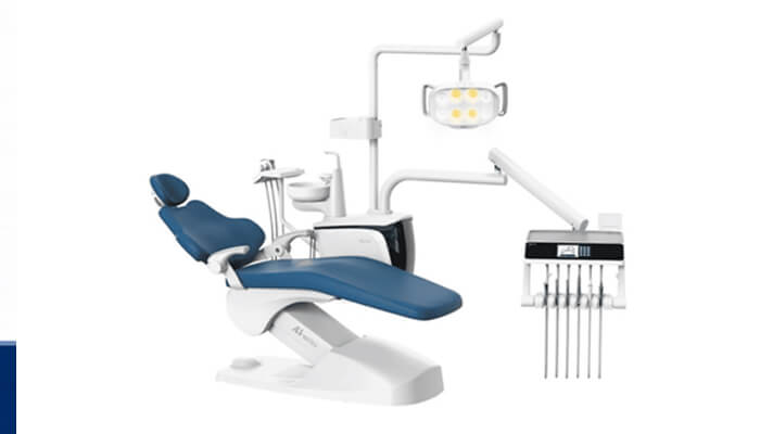 Gfc vbg bvg bn 1 | tycoonstory media Blue reclining dental chair with overhead light and attached tool arms in a white clinical unit.