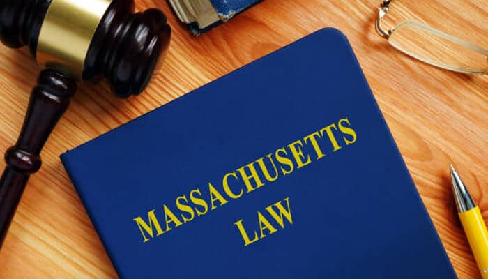 How massachusetts law treats these claims | tycoonstory media Motorcycle and bicycle accidents legal context represented by a massachusetts law book on a desk with a gavel, symbolizing state regulations, liability rules, and personal injury laws related to road accidents involving riders and cyclists.