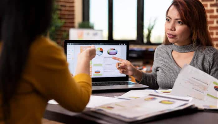 Find the leak between the ad and the deal - tycoonstory | tycoonstory media Two colleagues in a meeting review charts on a laptop while one points at the screen.