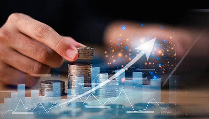 Hjgbnnbh 1 | tycoonstory media Hand stacking coins with a rising financial graph and upward arrow, illustrating growth and long-term wealth creation through real estate investments under securing your wealth-building strategy.