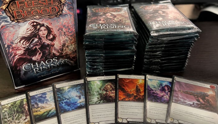 How many cards are in a chaos rising master set - tycoonstory | tycoonstory media Flesh and blood chaos rising booster packs and trading cards arranged on a tabletop.