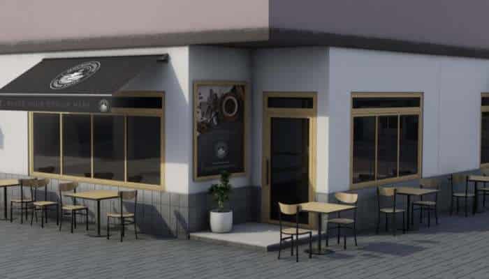 How outdoor business spaces are becoming a competitive advantage 2 | tycoonstory media Outdoor cafe seating along the corner of a white building with large windows, beige trim, a black awning, and multiple metal tables and chairs.