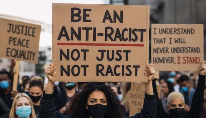 How to be anti racist 15 practical steps 1 | tycoonstory media How to be anti racist illustrated by a diverse group of peaceful protesters holding equality and anti-racism signs during a public demonstration.
