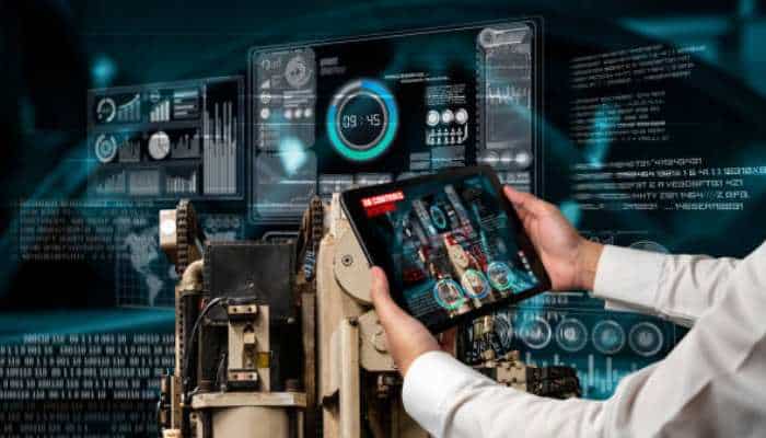 Industrial reinvention through the lens of a deep tech report 1 | tycoonstory media Technician uses a tablet to control a high-tech industrial machine with holographic dashboards in the background, showcasing automation.
