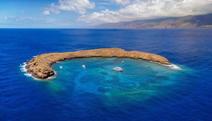Molokini crater - tycoonstory | tycoonstory media Aerial view of molokini crater, one of the best places to snorkel in hawaii, surrounded by clear blue ocean near maui.