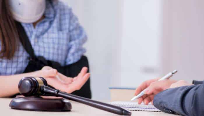 Personal injury claims 1 | tycoonstory media Gavel on a desk as a person in a plaid shirt gestures nearby while another person writes in a notebook.