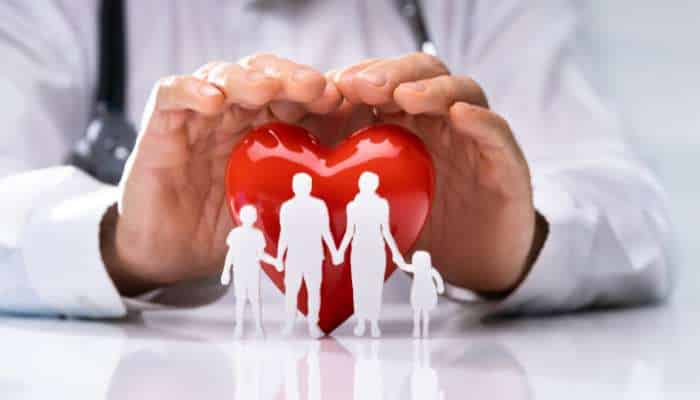 Travel insurance for parents travelling overseas key covers to look for 1 | tycoonstory media Hands shelter a red heart cradling a white family silhouette, symbolizing family health protection by care providers.