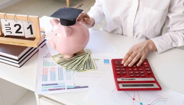 When do cri student loan payments begin - tycoonstory | tycoonstory media Cri student loans repayment planning with a graduation cap on a piggy bank, calculator, cash and financial documents, illustrating student loan payment schedules, budgeting strategies and education loan management in 2026.