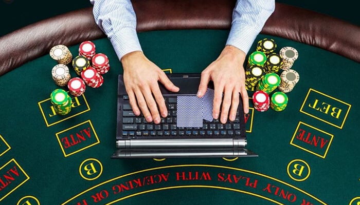 Bonuses are designed to give you extra playing time - tycoonstory | tycoonstory media Person using a laptop at a casino-style betting table, with stacks of poker chips and betting areas around.