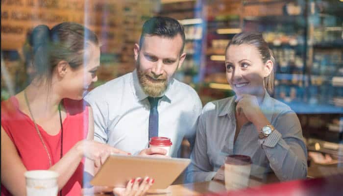 Start with the questions customers actually ask - tycoonstory | tycoonstory media Local customers discussing services with a business professional in a café, highlighting trust, engagement, and local business relationships.
