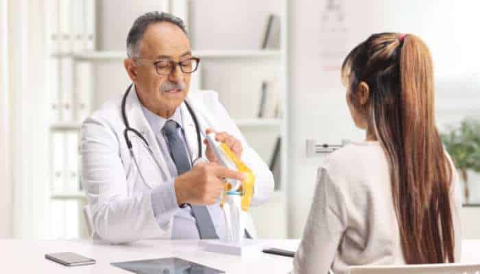 Differences in surgical accuracy between psi and robotic knee replacement | tycoonstory media Orthopedic surgeon explaining a knee model to a patient during consultation about psi vs. Robotic knee replacement treatment options.