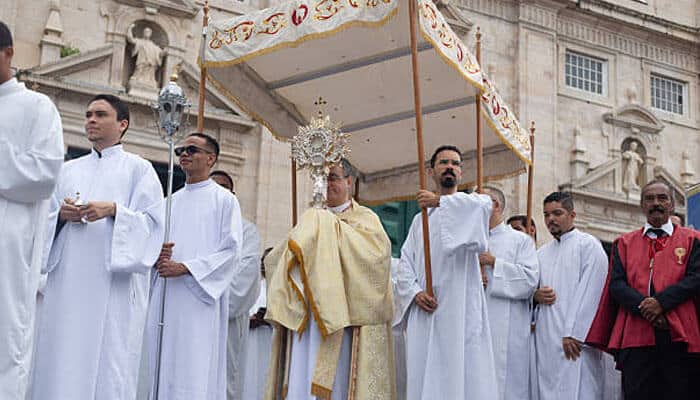 Canopy acquisition and maintenance: | tycoonstory media Processional canopies carried above the blessed sacrament during a corpus christi procession with clergy and parish participants.