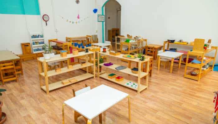Furnish a new preschool classroom 1 | tycoonstory media Montessori classroom with wooden low shelves, small tables and chairs, and scattered educational materials on shelves and tables.