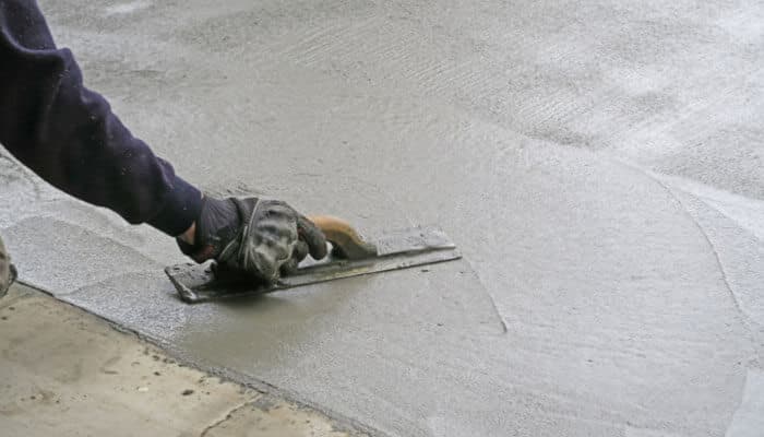 How to repair a concrete step with quikrete quick-setting cement - tycoonstory | tycoonstory media Worker smoothing fresh quikrete quick-setting cement with a hand trowel to create an even concrete repair surface on a damaged step or slab.