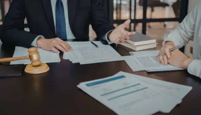 Top-rated new jersey personal injury law firms to know about 1 | tycoonstory media Two professionals discuss documents at a desk with a gavel and law books on the table.
