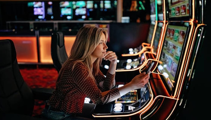Untitled-1 | tycoonstory media Woman using a slot machine in a casino while reviewing the screen, illustrating how a casino bonus may fit different stages of play.