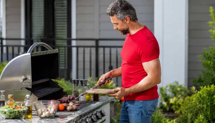 Gas bbqs are completely maintenance-free - tycoonstory | tycoonstory media Man cooking outdoors on a gas bbq while preparing fresh food for a relaxed backyard meal and entertaining at home.