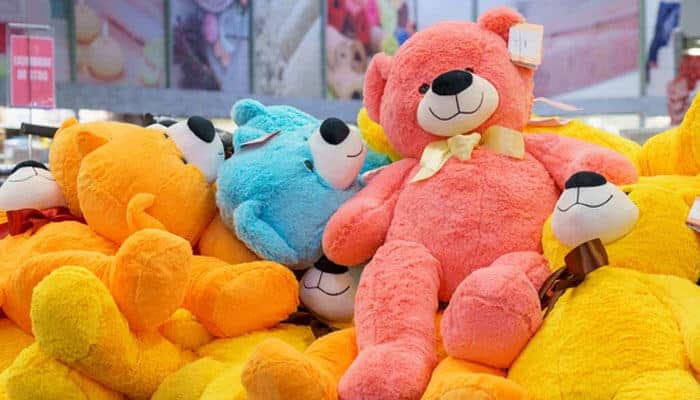 They make brand characters more tangible - tycoonstory | tycoonstory media Colorful plush teddy bears piled in a store display, including pink, orange, and blue bears.