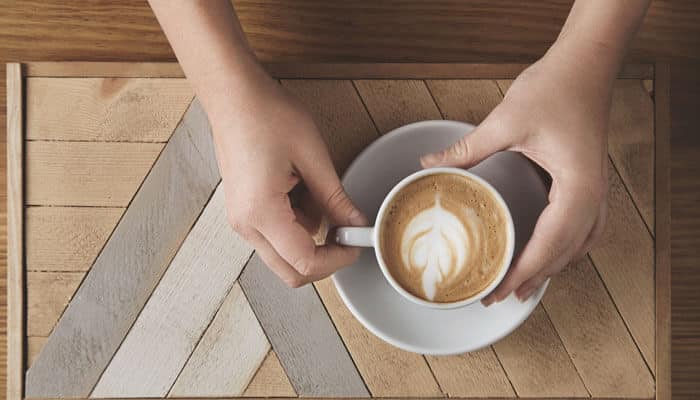 Where did the flat white come from - tycoonstory | tycoonstory media Difference between latte and flat white illustrated by a top-view cup of espresso with smooth microfoam and latte art on a wooden café table.