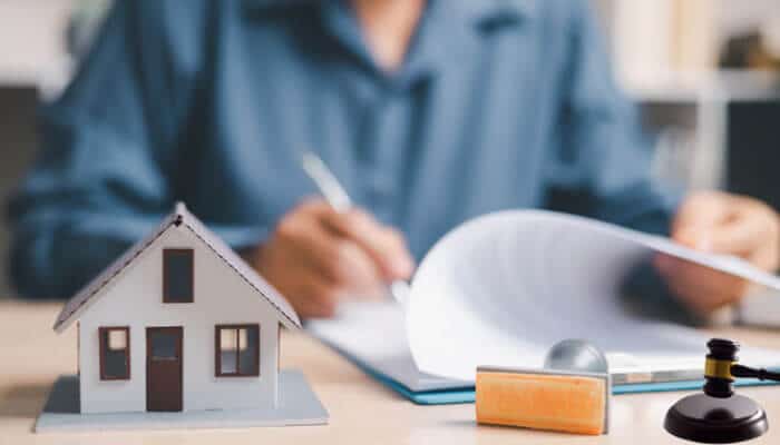 Why mortgage marketing requires extra compliance attention -tycoonstory | tycoonstory media Mortgage marketing company compliance review showing a model home, mortgage documents, approval stamp, and gavel, representing regulatory oversight of mortgage advertising, loan terms, rates, apr disclosures, and marketing claims.