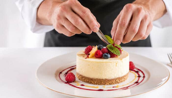 How long does philadelphia cheesecake no bake take to set? - tycoonstory | tycoonstory media Philadelphia cheesecake no bake being decorated with fresh berries by a chef, showing the creamy texture and homemade preparation process of this chilled dessert.